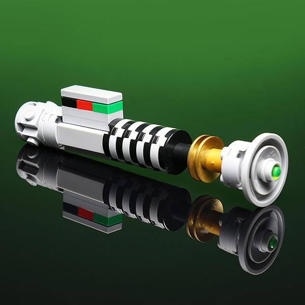 Luke's Green Mini Saber made using LEGO parts - B3 Customs displayed on a reflective surface with a detailed black, white, and gold hilt and a green tip against a green background.