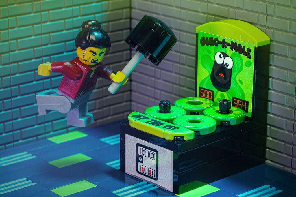 A LEGO minifigure with a determined expression playing Guac-A-Mole - Custom Arcade Whac-A-Mole Set made using LEGO parts - B3 Customs, holding a mallet ready to hit the popping moles in a detailed arcade setting.