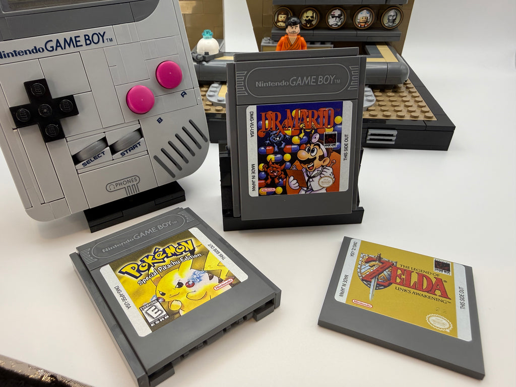 A Nintendo Game Boy console with custom printed game cartridges displayed, featuring classic titles Mario, Pokémon, and Zelda, highlighted by the Printed Tile Upgrade Kit for GB Set Game Cartridge.