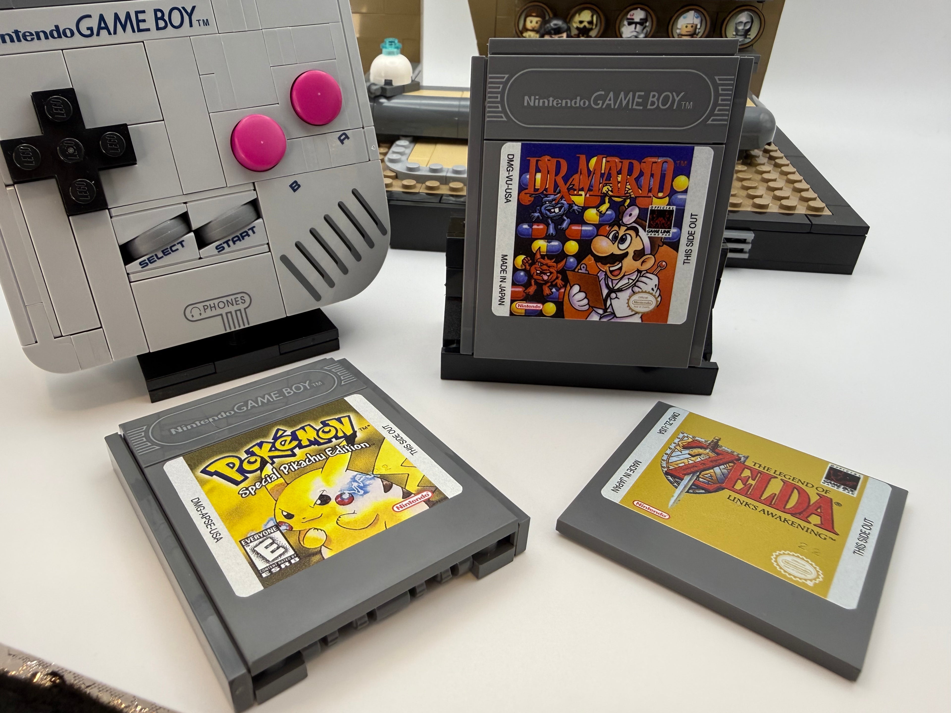 Close-up of custom LEGO bricks arranged to resemble a Nintendo Game Boy with game cartridges featuring printed tiles from the Printed Tile Upgrade Kit for GB Set Game Cartridge, including Pokémon, Dr. Mario, and Zelda designs.