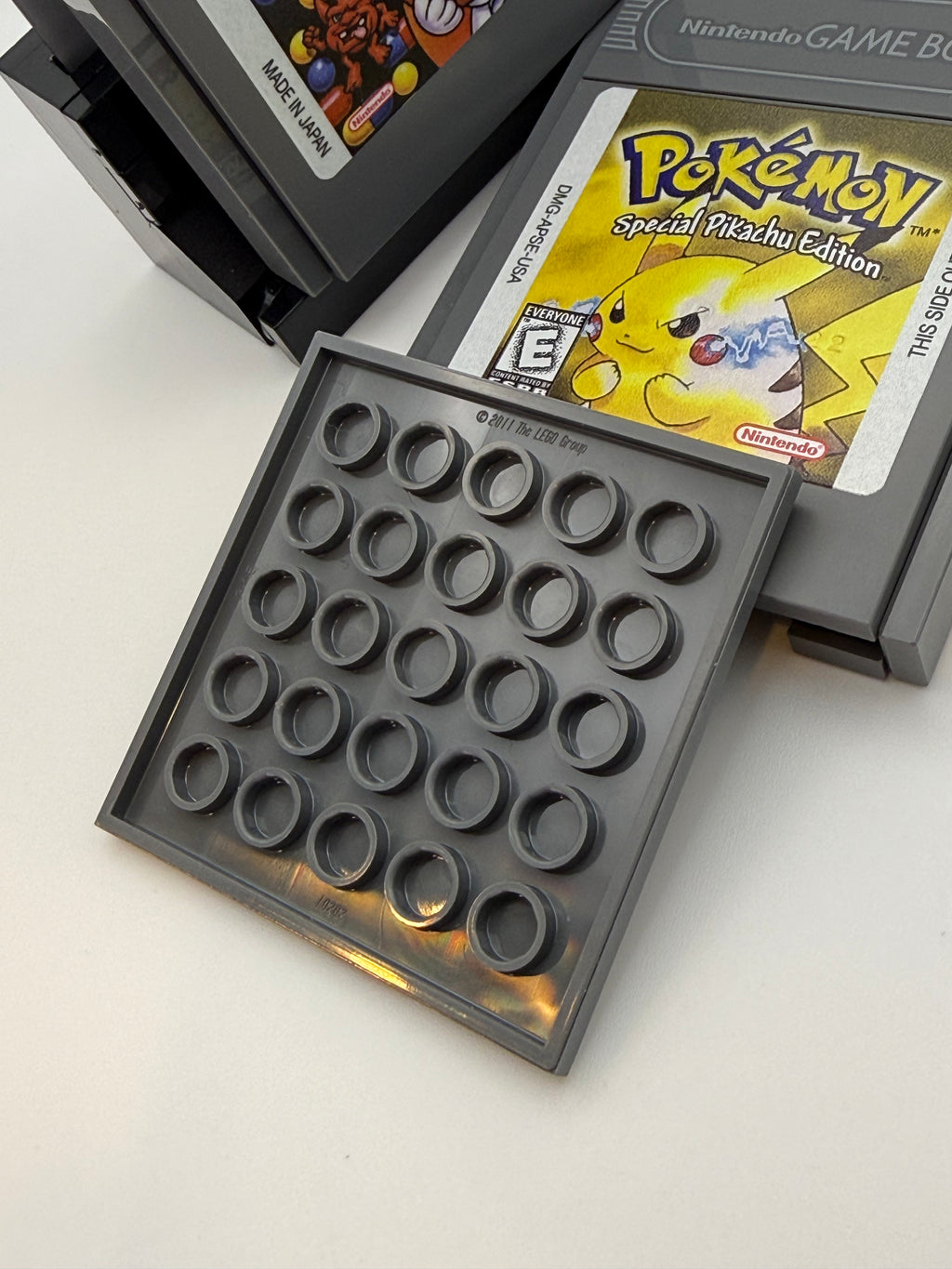 Printed Tile Upgrade Kit for GB Set Game Cartridge shown with a grey plastic custom printed tile designed to fit a Nintendo Game Boy cartridge, displayed next to classic game cartridges including Pokémon Special Pikachu Edition.