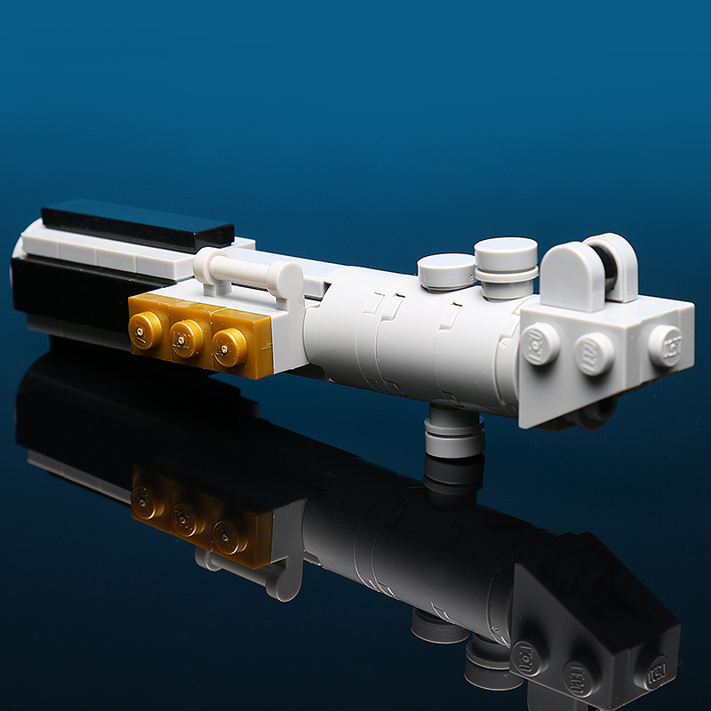 Close-up of a detailed LEGO-built blue and white lightsaber hilt model on a reflective surface, part of Luke's Blue Lightsaber Building Kit made using LEGO parts - B3 Customs.