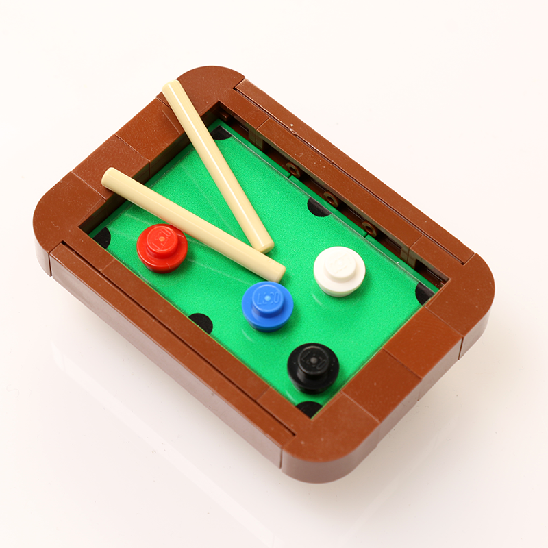 A detailed Pool Table Building Kit made from LEGO parts by B3 Customs shown with a green playing surface, brown frame, two beige cues, and colorful round LEGO balls.