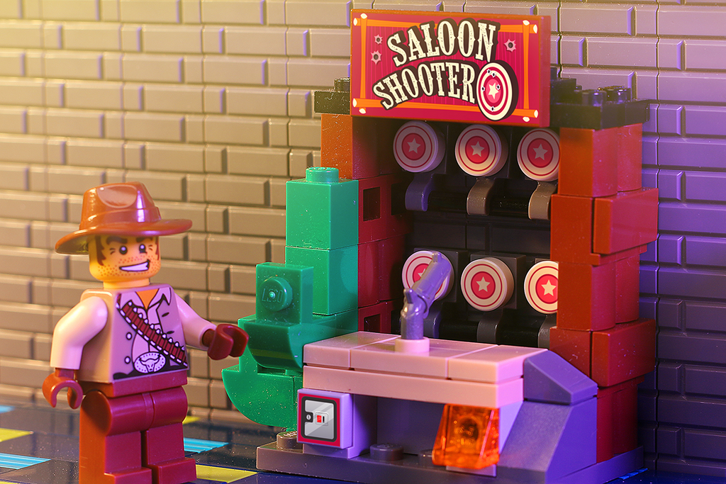 Saloon Shooter Arcade Game made using LEGO parts by B3 Customs displayed with a LEGO cowboy minifigure standing next to a colorful arcade game machine.