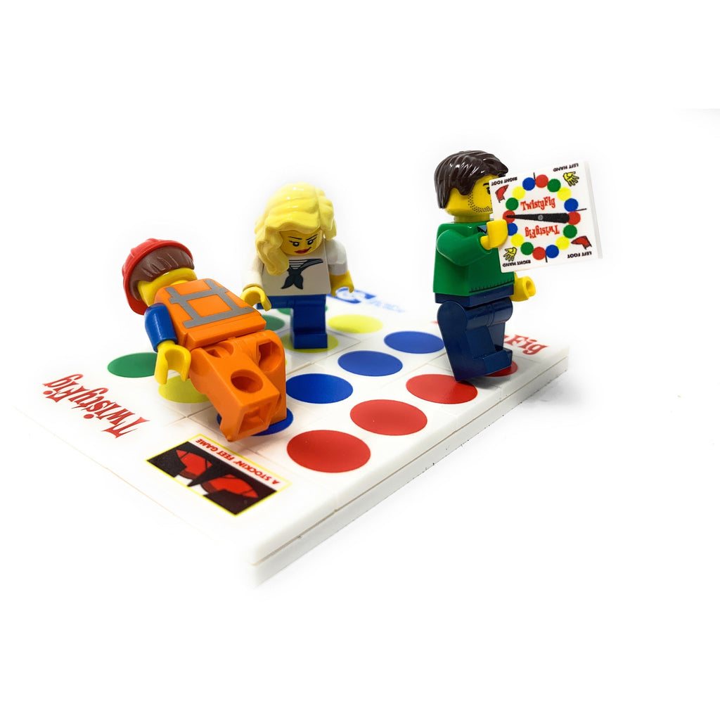 Three LEGO minifigures positioned on a colorful TwistyFig Minifig Board Game Building Set made using LEGO parts by B3 Customs, featuring custom printed tiles and instructions.